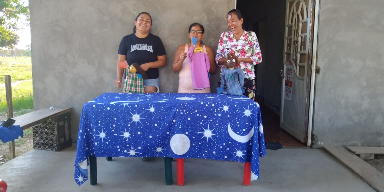 Women of the NAR La Pista community, a former FARC guerilla group in Colombia, laugh as they use CEPALC puppets to narrate a story. (Photo courtesy of CEPALC).