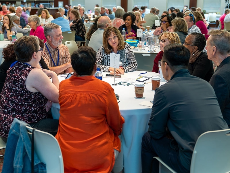 A group people at a conference sitting at a round table.